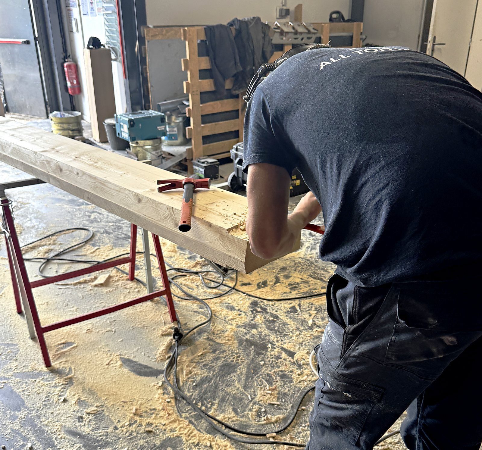 Compagnon ALL TOITURES taillant une pièce de charpente à l'atelier
