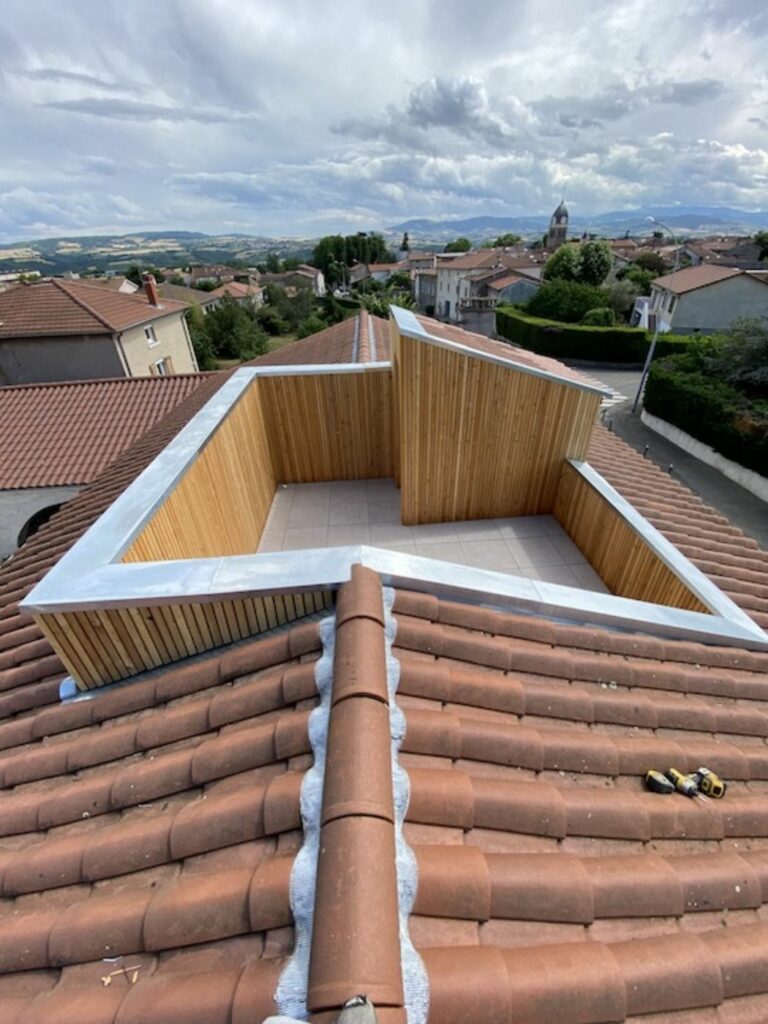 Terrasse tropézienne terminée avec bardage bois vertical et couvertines, intégrée dans la toiture en tuiles, Beauvallon (69)